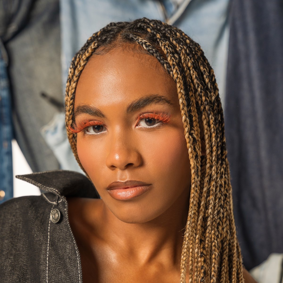 Close portrait: luminous skin and a coral-orange wash across the lid and lower lash line