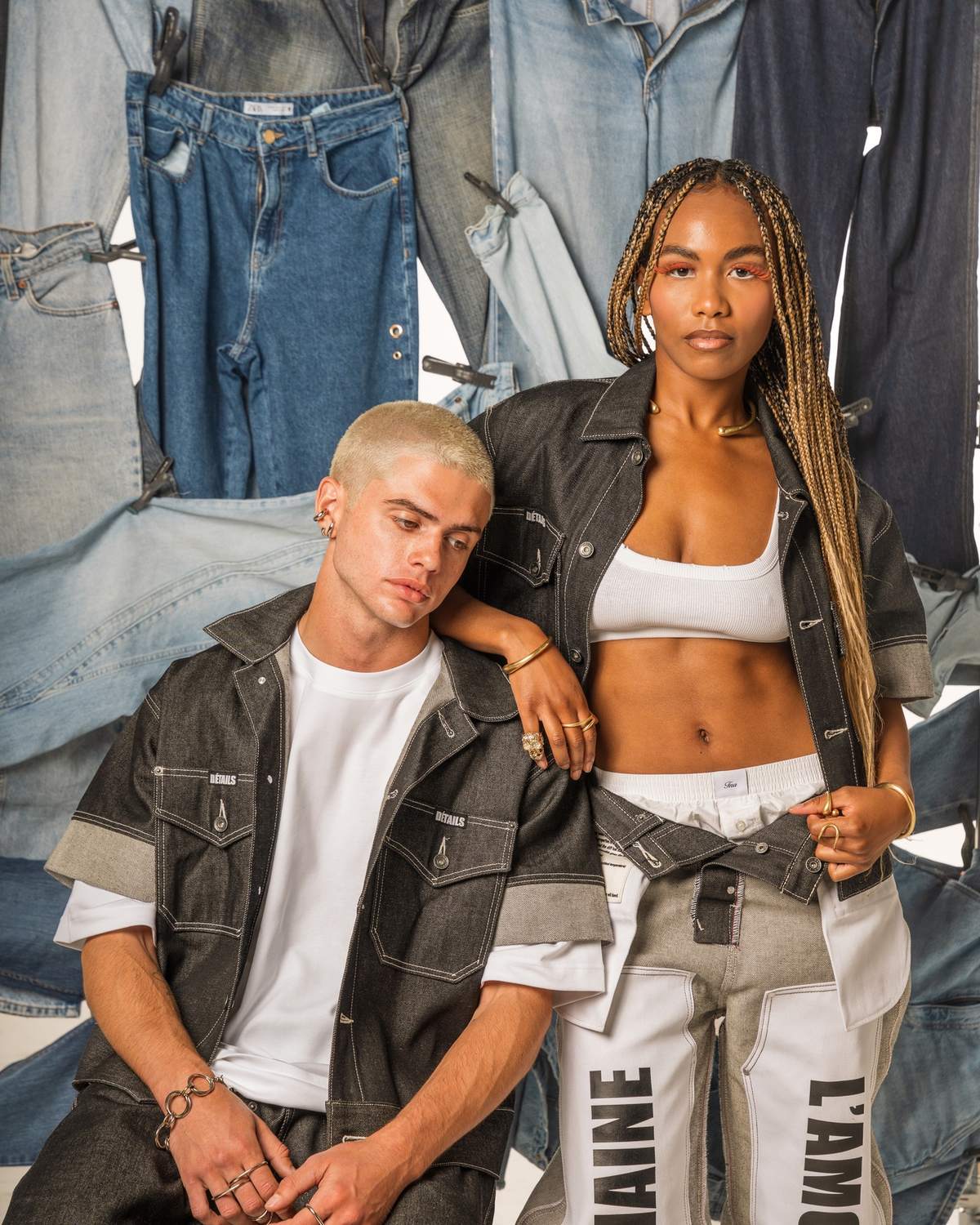 Two models against the hanging denim backdrop, the wash range running light to near-black behind them