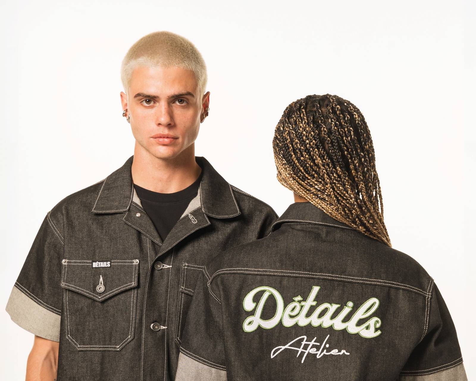 Two models in matching raw denim sets, one facing the camera and one turned away to show the Détails Atelier script embroidered across the jacket back