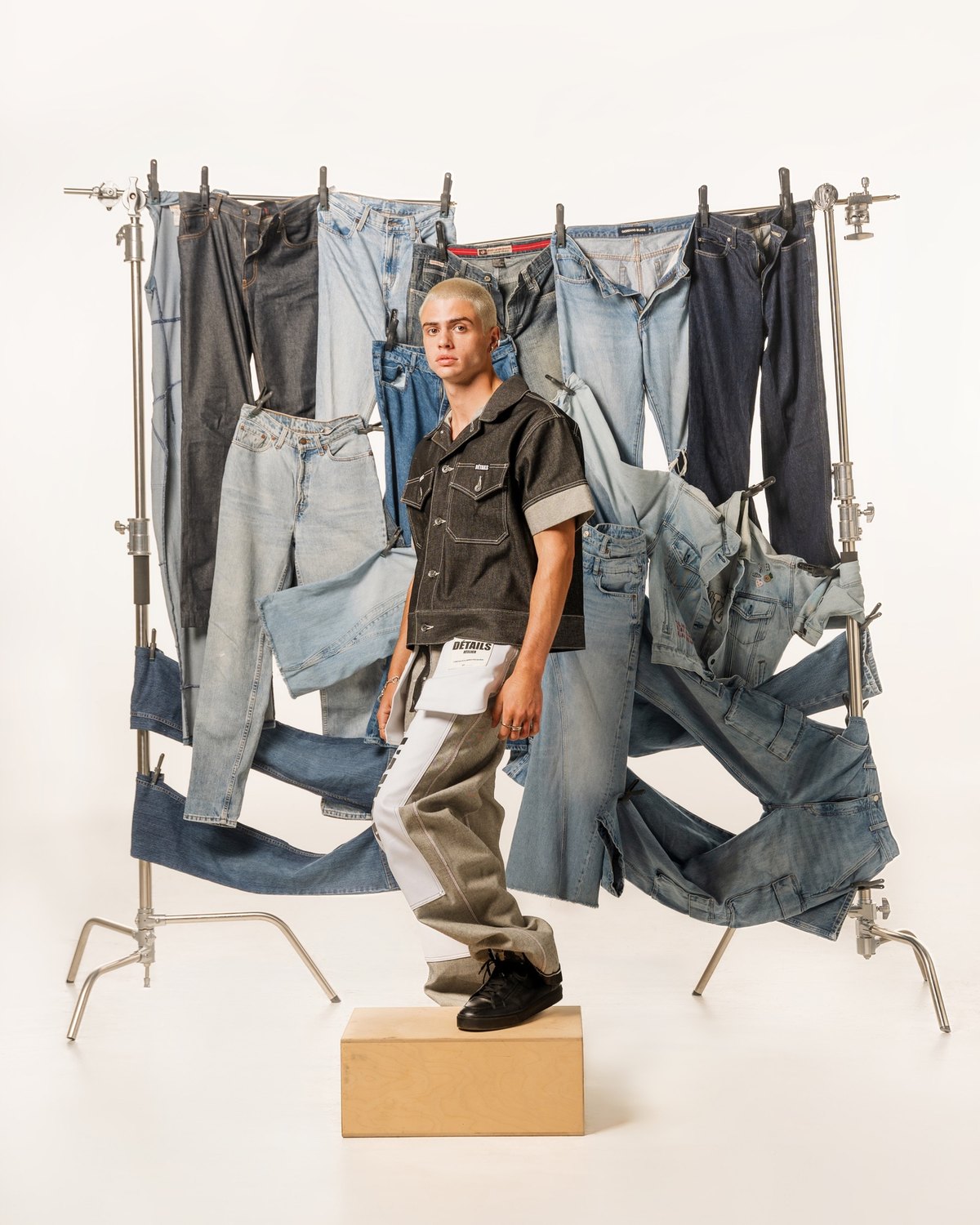 The full set: jeans clipped along a crossbar in two tiers, a birch apple box on the floor