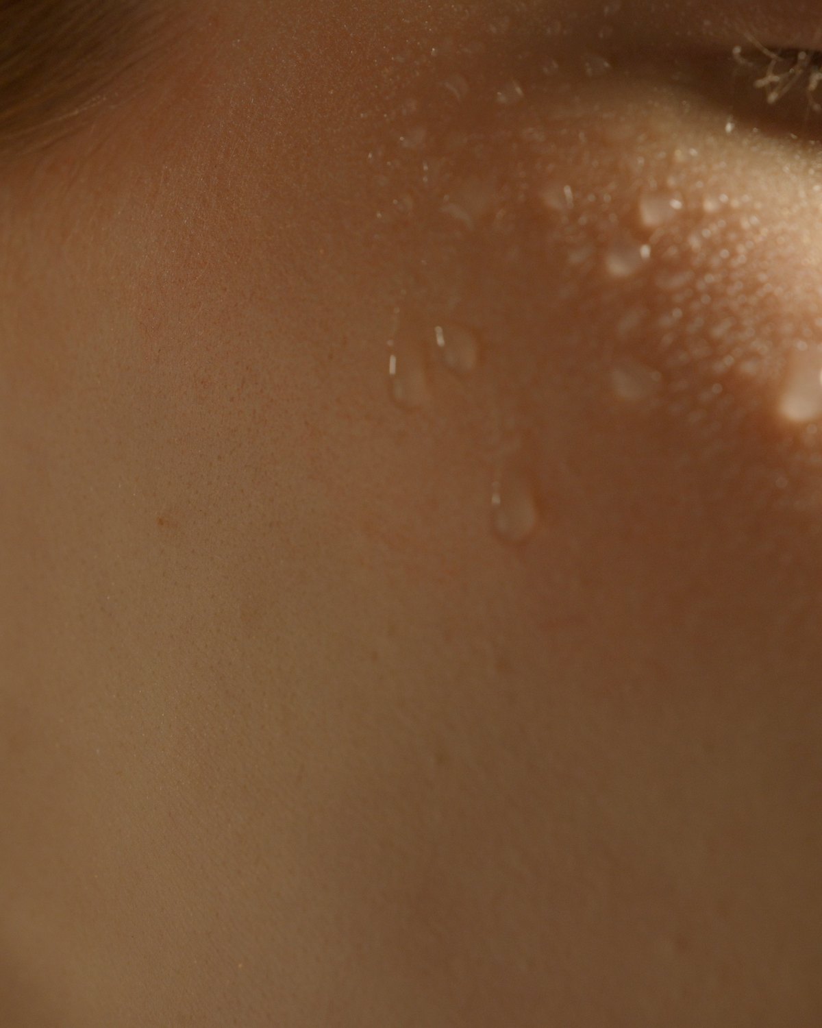 Macro of a dewed cheek, freckles and water beading legible