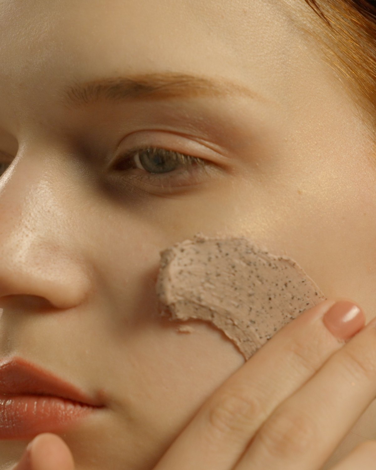 The clay mask worked across the cheek with two fingers