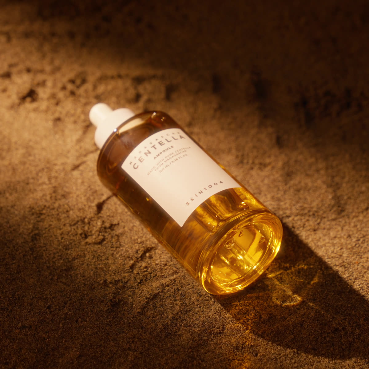 The ampoule standing upright in pale sand