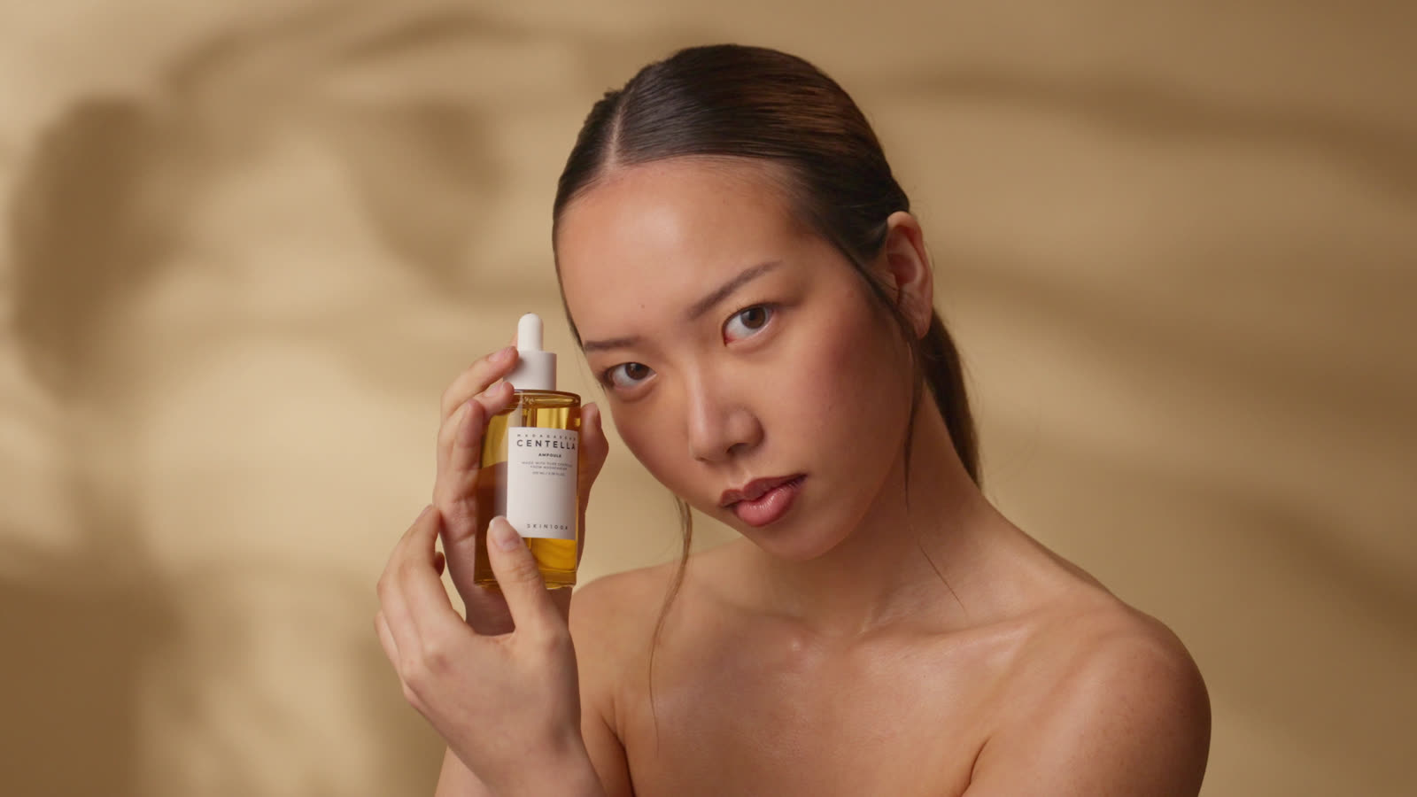 The model holds the ampoule to her temple, wide