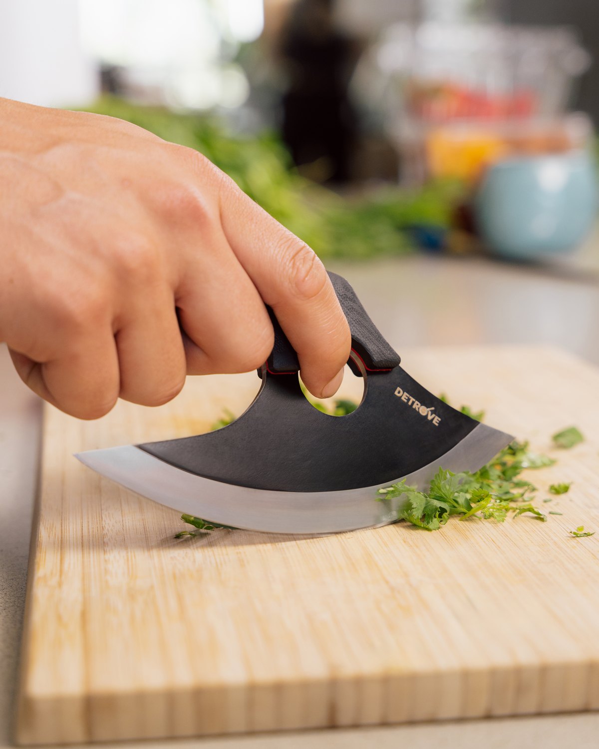 The rocking mince through a pile of herbs on a bamboo board
