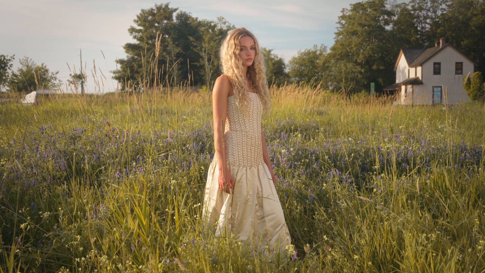 The gown walked along the mown dike edge, meadow and treeline behind
