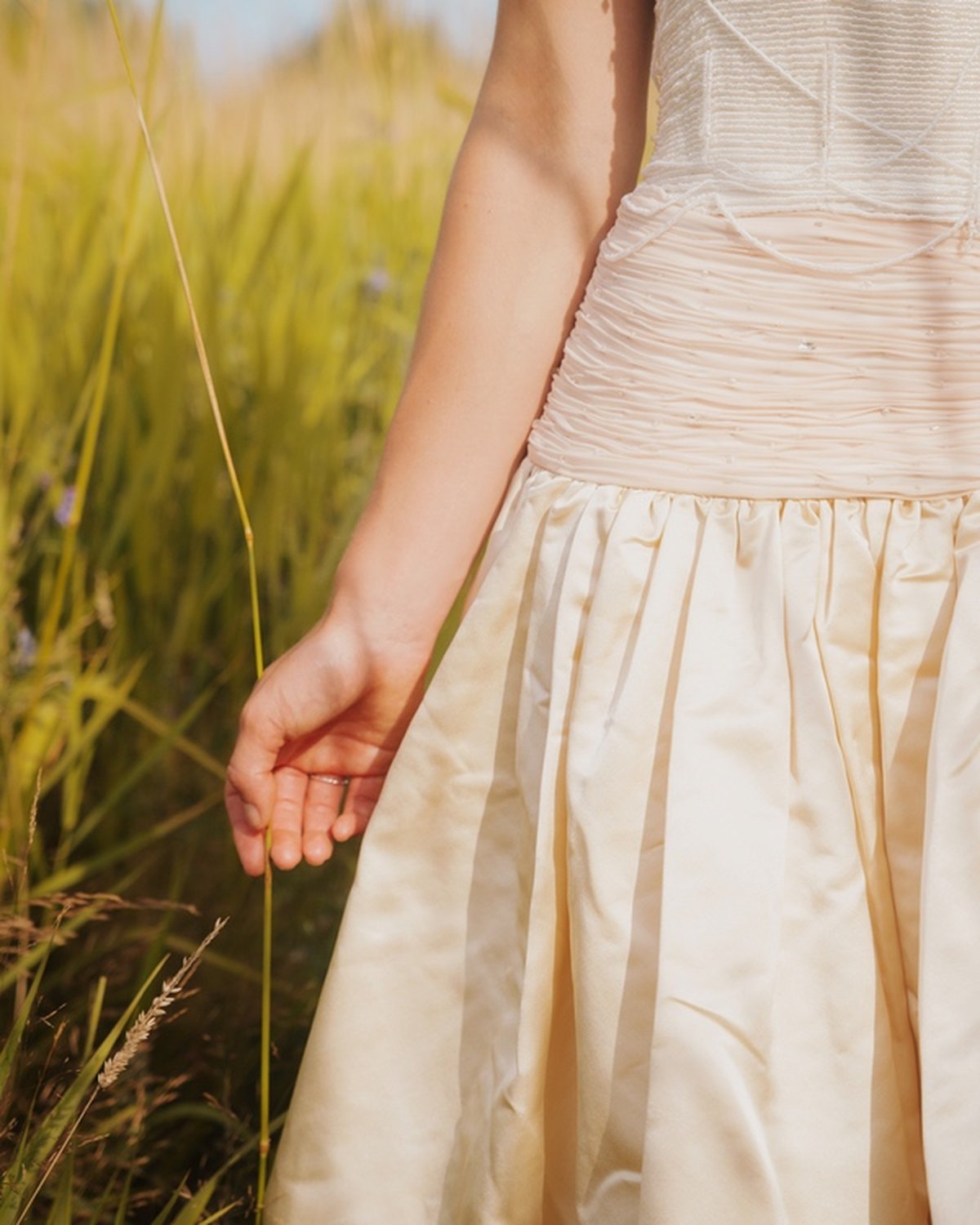 A hand at the hip, the satin skirt falling in full drape