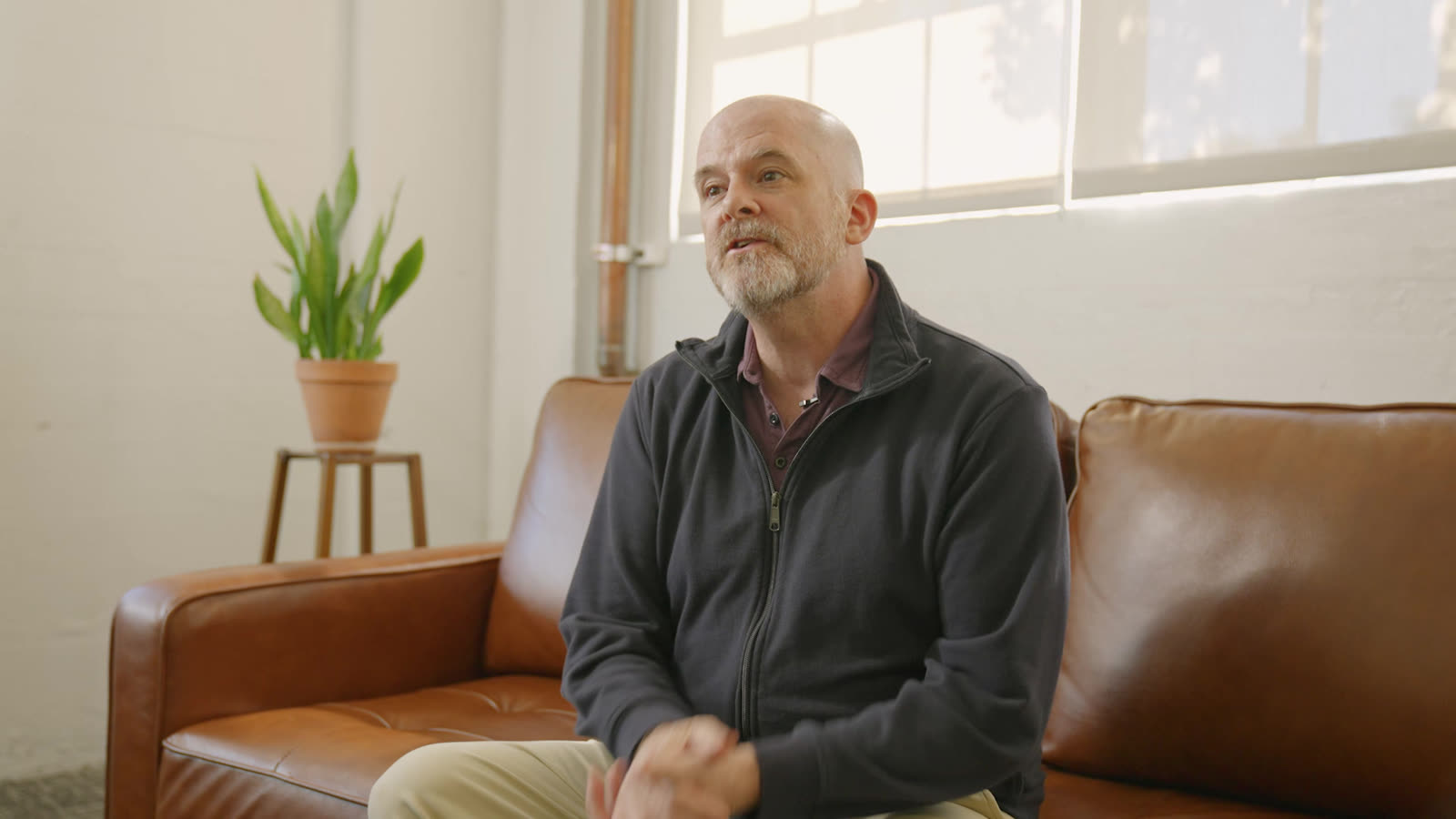 Casey Lippmeier speaking, seated on a leather couch in window light