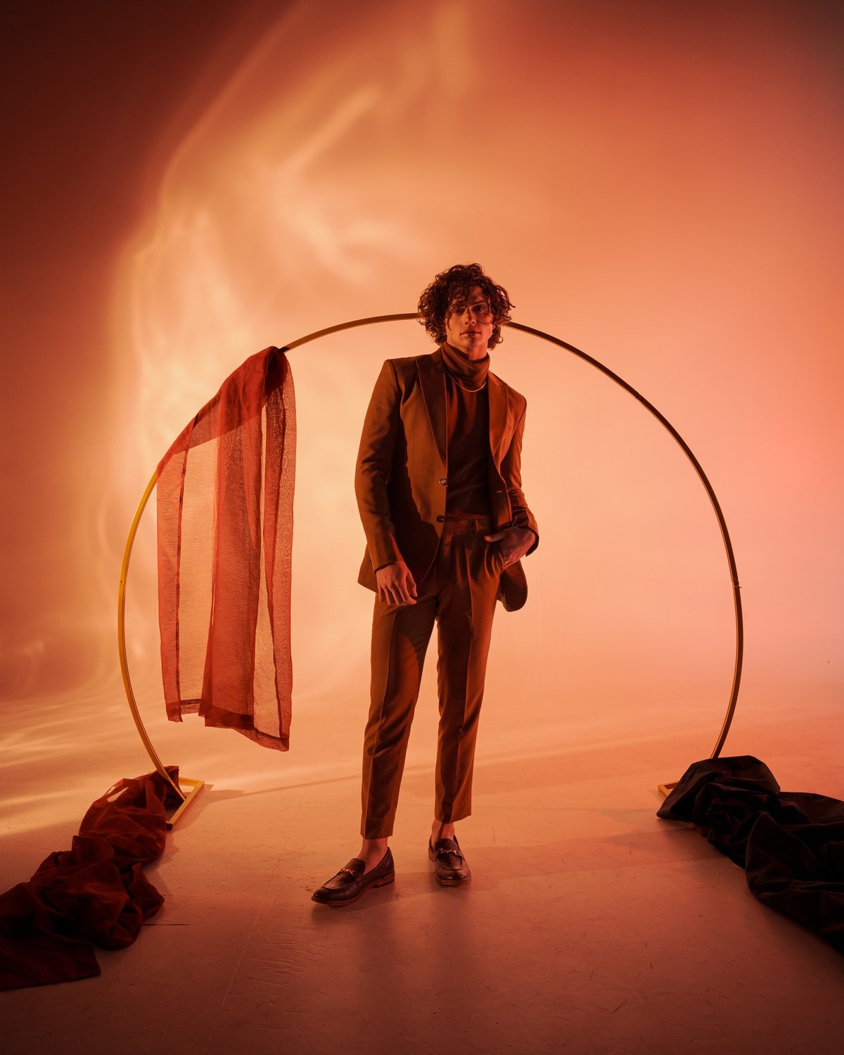 The same set in portrait: the gold hoop, the draped sheer panel, the figure inside it