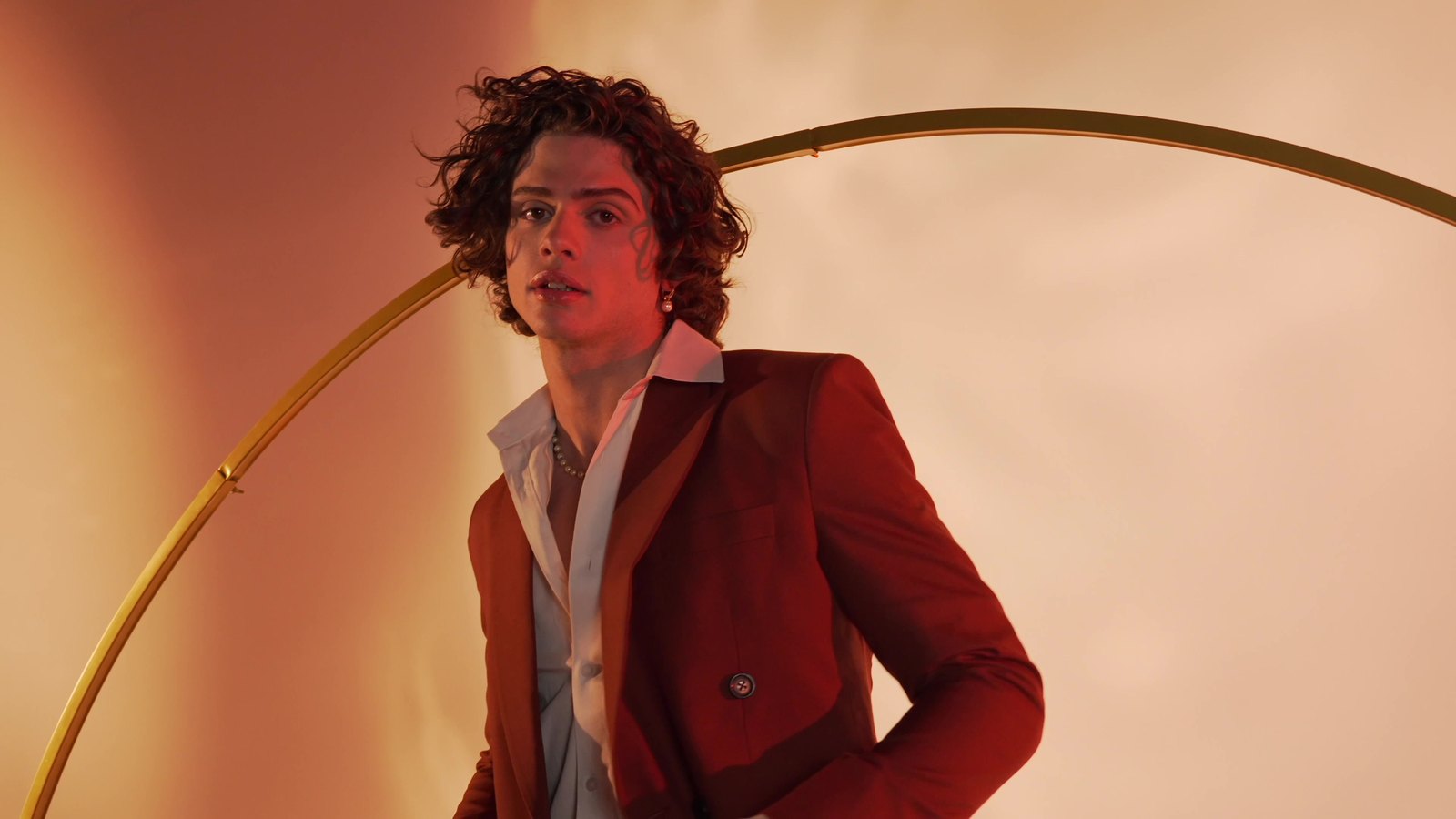 The rust suit against the gold arc, three-quarter