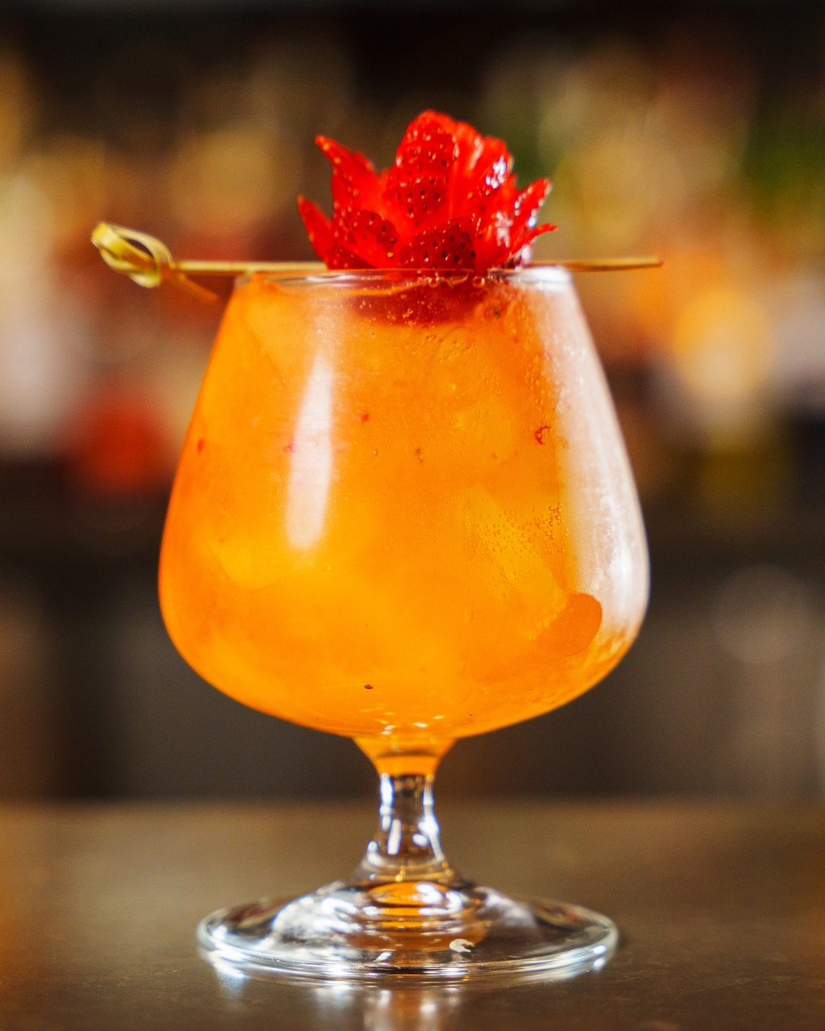 A garnished cocktail isolated on the bar top against a defocused backbar