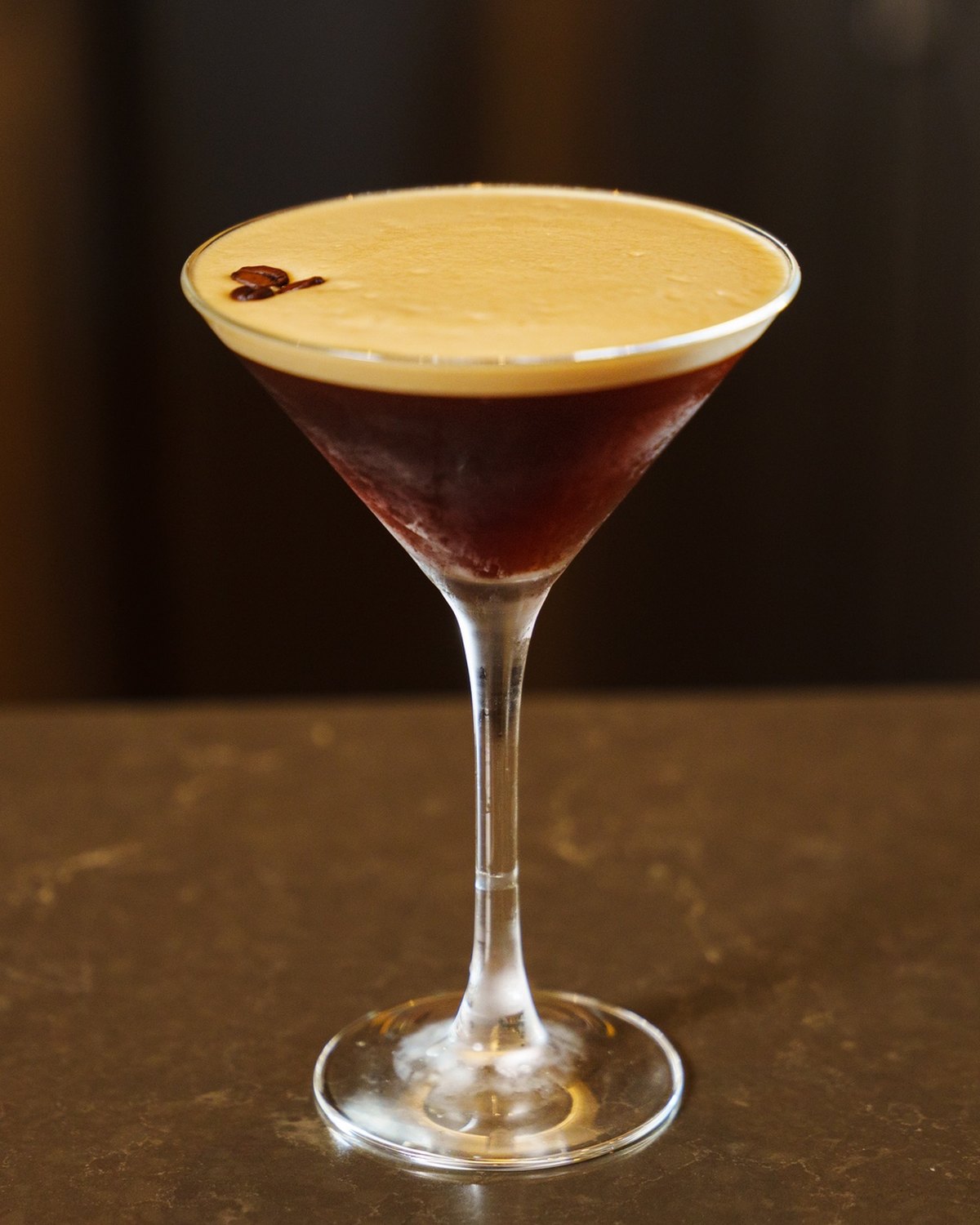 An espresso martini on the bar top, backbar defocused behind
