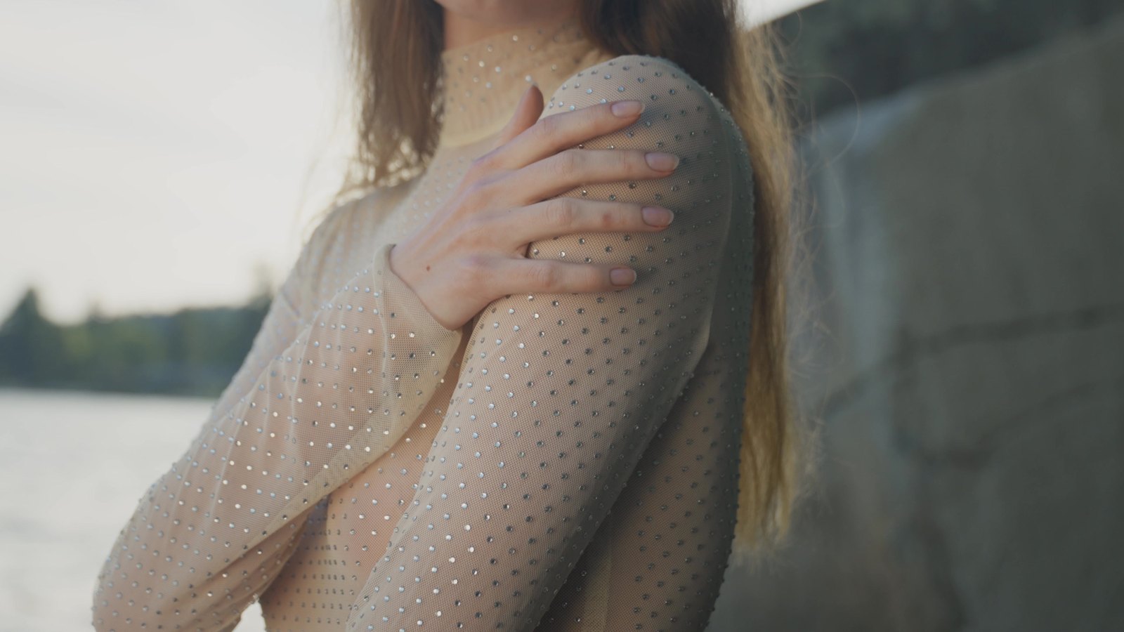 Close detail of an arm and shoulder in sheer mesh against a stone seawall