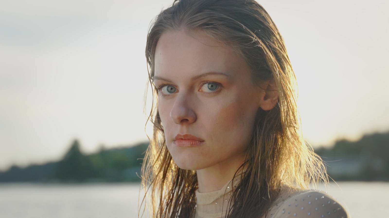 Backlit beauty close-up of a model with wet, salt-kissed hair looking directly to camera